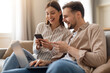 © Prostock-studio - Excited couple sharing smartphone, man with laptop