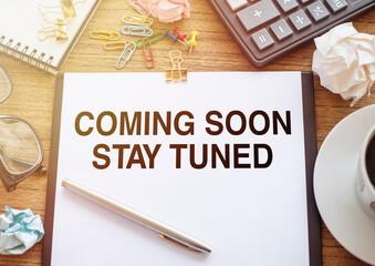 Coming Soon Stay Tuned wording on a white paper on wooden office background