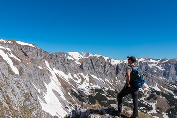 Poster - Hiker man with panoramic view of majestic mountain peak Ringkamp in wild Hochschwab massif, Styria, Austria. Scenic hiking trail in remote Austrian Alps on sunny day. Wanderlust in alpine spring