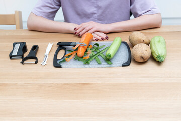 Close-up shot of a woman peeling vegetables using special vegetable peelers in the kitchen