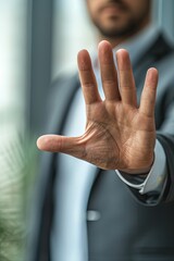 Closeup of the hand of a businessman showing stop, saying no or not accepting a deal in an office at work. A powerful hand gesture signifies the rejection of an offer.