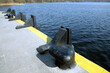 Black heavy bollards on empty river pier edge on seaside diagonal view on sunny day