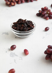 Wall Mural - Dark dried sweet raisins on light background with red grapes.