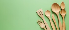 Rustic Wooden Spoons And Forks Set On Vibrant Green Background For Food Photography And Kitchen Themes