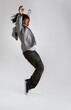 Kid, fashion and dance with energy in studio with hoodie in streetwear on grey background. African, child and cool teenager or dancer with casual style, clothes and balance on shoes in mockup