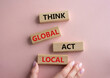© Natallia - Think global act local symbol. Wooden blocks with words Think global act local. Beautiful pink background. Businessman hand. Business and Think global act local concept. Copy space.