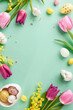 Easter awakening: festive spirit in every detail. Top view vertical shot of pink tulips, patterned eggs, adorable bunny figures, and fluffy mimosa on teal background with space for greetings or ads