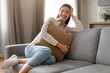 © Prostock-studio - Joyful young woman relaxing with pillow on the sofa at home and smiling