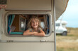 © Ala - A cheerful girl looks out of the window of a motorhome