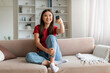 © Prostock-studio - Happy asian woman with remote controller in hand watching tv at home