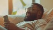 Smiling bearded African man working at home while sitting on the sofa.Concept of young people using mobile devices.Blurred background.