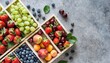 summer fruit and berry variety flat lay of ripe strawberries cherries grapes blueberries pears apricots figs in wooden eco friendly boxes over grey background top view copy space