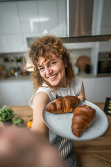 Wall Mural - One adult caucasian woman stand in the kitchen with fresh croissant