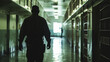 Man Walking Down Jail Cell Hallway, Silhouetted Security Guard Patrolling Dimly Lit Prison Corridor