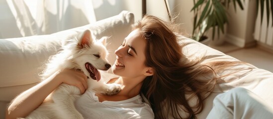 Wall Mural - Relaxed woman enjoying leisure time lying on comfortable couch with her lovely pet dog