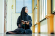 © maya1313 - Ramadan, The image of an Asian Muslim woman in the Islamic religion in hijab in black color. reading the Quran and having a happy smiling face Staying in a beautiful mosque out of respect for God.