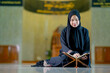 © maya1313 - Ramadan, The image of an Asian Muslim woman in the Islamic religion in hijab in black color. reading the Quran and having a happy smiling face Staying in a beautiful mosque out of respect for God.