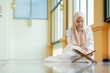 © maya1313 - Ramadan, quran, The image of an Asian Muslim woman in the Islamic religion in hijab in cream color. reading the Quran and having a happy Staying in a beautiful mosque, Arabic word Holy Al Quran.