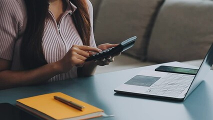 Wall Mural - Woman hand holding white mobile phone on a table with a laptop in office.