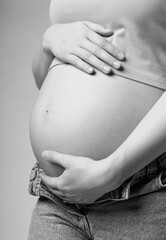 Wall Mural - Black and white photo of young female touching with hands her naked belly. Baby expectation concept.