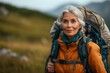 Explore the beauty of nature as an active senior woman enjoys a hiking trip, adorned with a backpack, amidst picturesque landscapes.