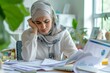 © Milkghost - Stressed Middle Eastern accountant with paperwork at desk