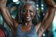 Strong happy African American woman working out and exercising her muscles in the gym. Senior athletic woman raising her hands up