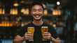 Portrait of an happy smiling Asian young man wearing a black tee, standing in a bar while holding two glasses of beer in his hands