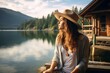 © Rax Qiu - A female tourist enjoying the peaceful lakeside scenery, with a cabin and mountains in the background