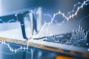 Poster - Close up of eyeglasses and laptop with glowing and growing business chart on blurry blue background. Financial growth, trade and stock concept. Double exposure.