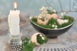 Easter decoration - candle, eggs shells with moss, feathers, flowers on a plate, blue and grey background.