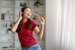 © Prostock-studio - Cheerful asian woman singing joyfully into hairbrush like a microphone