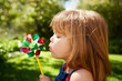 Young girl, outdoor and blowing pinwheel, garden and enjoying freedom of outside and happy. Pretty little child, backyard and summer for playing, toy and windmill for school holidays and happiness