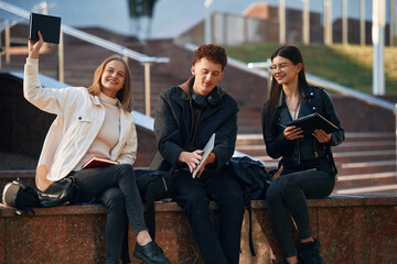 Wall Mural - With notepad. Three young students are outside the university outdoors