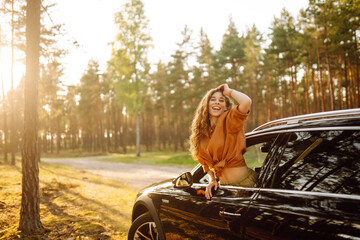 Happy woman leaning out of car window on summer road trip travel vacation.