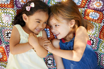 Canvas Print - Happy, nature and girl kids on blanket playing together in outdoor park or garden on vacation. Smile, bonding and high angle of young children friends relaxing in field on holiday or weekend.