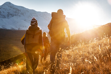 Wall Mural - Group of hikers tourists with backpacks walks in sunset mountains. Active lifestyle concept