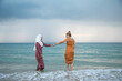 © Connect Images - Two young women, best friends one is wearing a hijab having fun and enjoying time at the beach.
