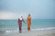 © Connect Images - Two young women, best friends one is wearing a hijab having fun and enjoying time at the beach.