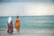 © Connect Images - Two young women, best friends one is wearing a hijab having fun and enjoying time at the beach.