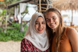 © Connect Images - Smiling portrait of two female best friends, one is wearing a hijab in a beach resort in southern Thailand.