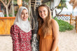 © Connect Images - Portrait of two female best friends, one is wearing a hijab in a beach resort in southern Thailand.