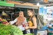© Connect Images - Two young women one wearing a hijab buying fruit.