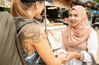 © Connect Images - Two young women one wearing a Hijab greet each other in a rural town in Thailand