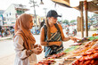 © Connect Images - Two young women one wearing a Hijab buying street food in a rural town in Thailand
