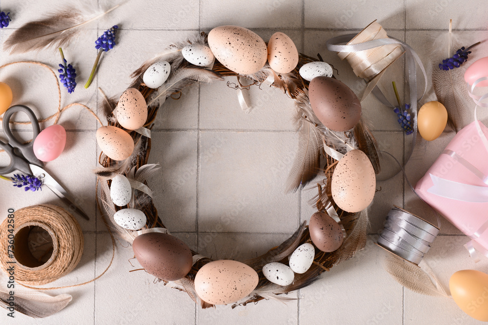 Composition with supplies for creating Easter wreath on white tile background