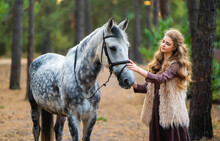 Portrait Of Beautiful Blonde Curl Girl In Medieval Dress And Fur Vest On  Nature With Horse. Young Worker In Rural Scene In Forest.Warm Colorful Art Work.
