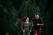 Fit couple jogging amidst a scenic mountain landscape, dressed in sporty attire