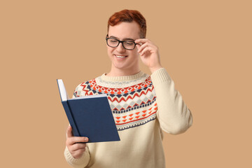 Wall Mural - Young man in eyeglasses reading book on color background