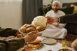 © TrueFrame Collective - Hands of young unrecognizable woman passing plate with homemade bread to guest over homemade food during family dinner